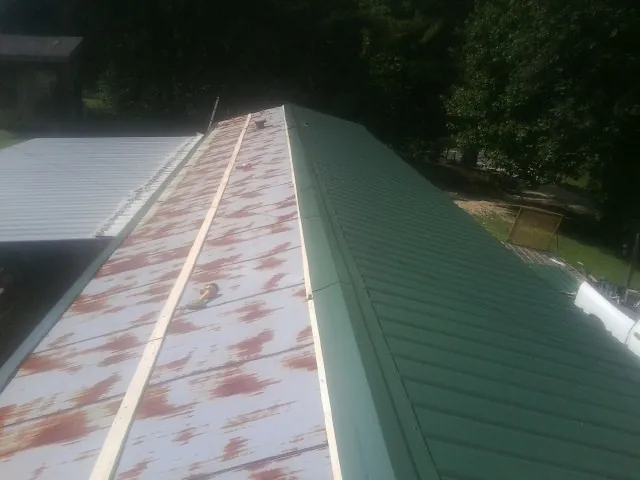 Old rusted panels beside newly installed green metal roofing — Wind Damage Roof Repair by Roofing Brothers in North Wilkesboro