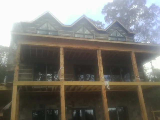 Dormers and porch framing on a large log home under construction — Roof Coating work by our crew in North Wilkesboro