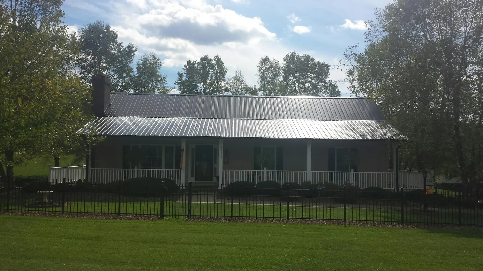 Gray metal roof on a brick ranch with a full width front porch — Gutter Guard Installation work by our crew in North Wilkesboro