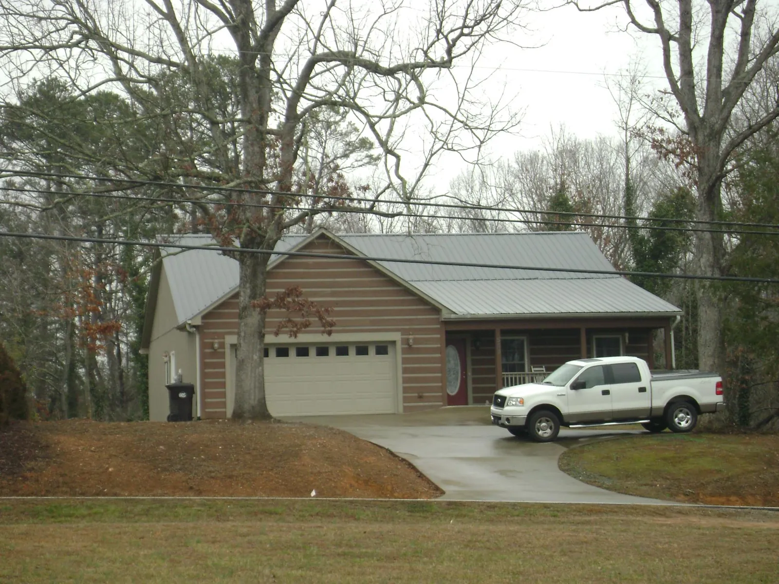 Gray metal roof on a log sided house with an attached two car garage in North Wilkesboro