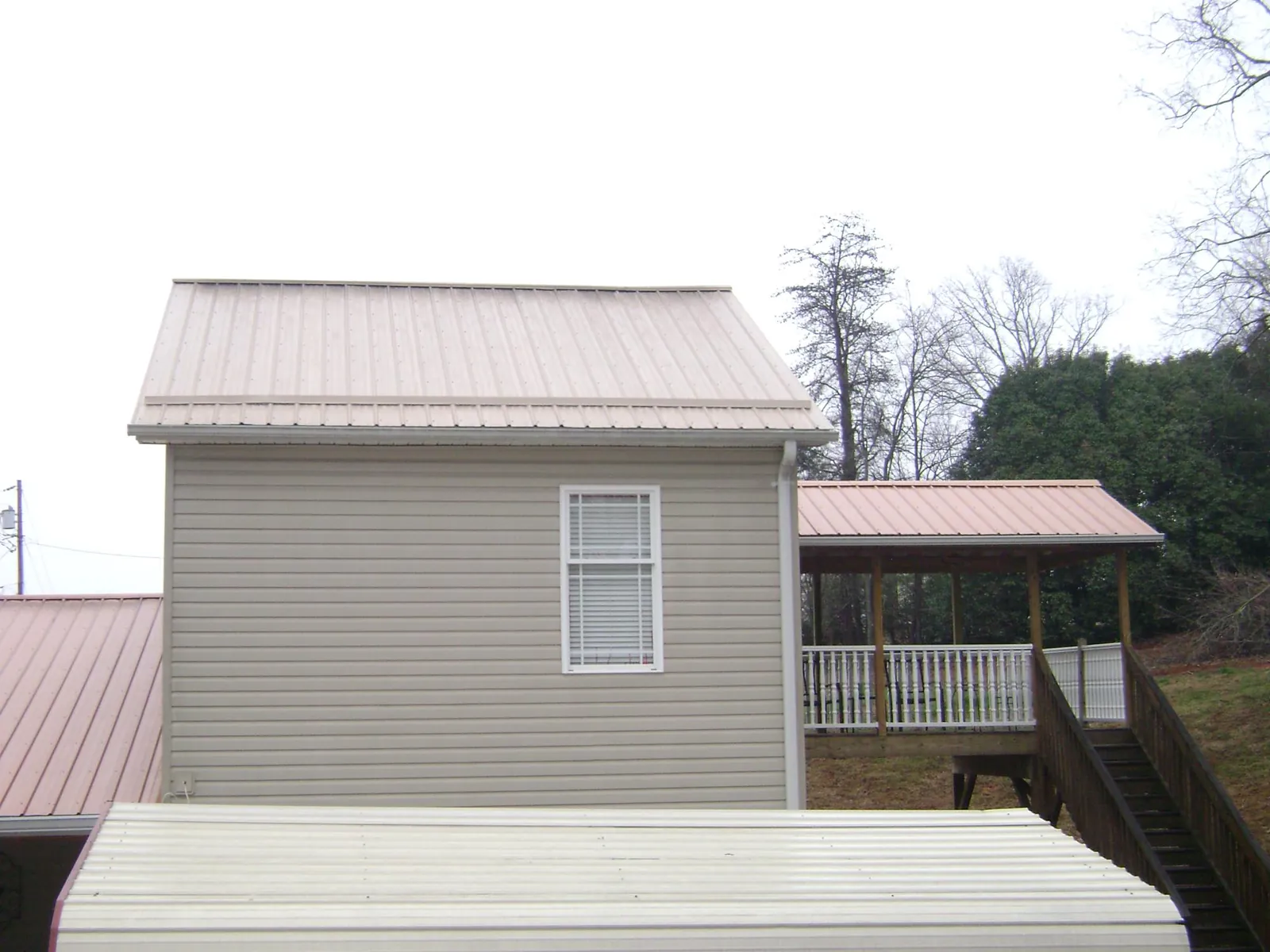 Tan metal roofs on a two story addition and attached porch, from a Roof Replacement job in North Wilkesboro