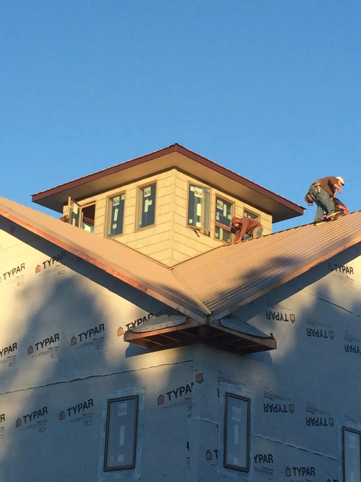 Roofers working around a rooftop cupola on a new metal roof at sunset — Roof Waterproofing in North Wilkesboro by Roofing Brothers